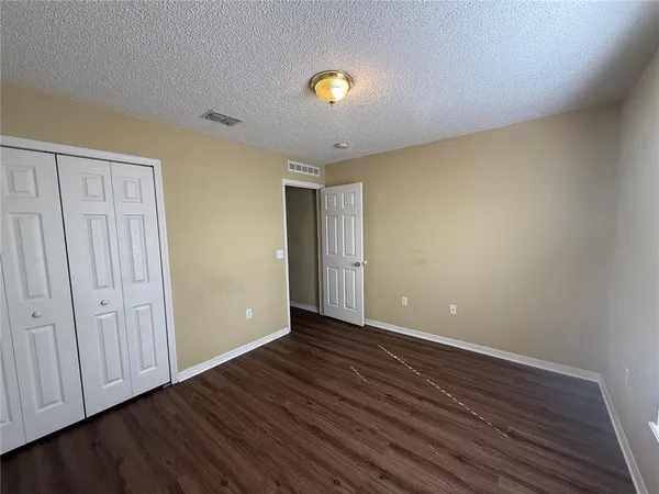 a view of an empty room with wooden floor and closet