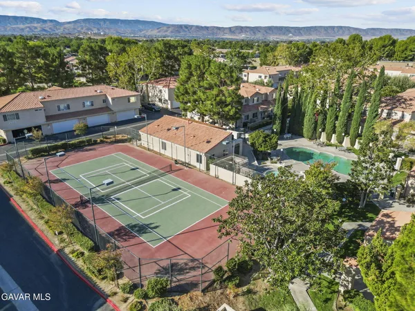 an aerial view of a tennis ground and a lots of residential buildings in the background