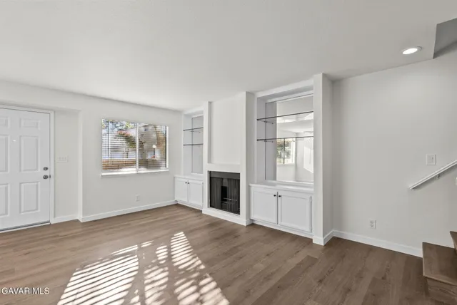 an empty room with windows and fireplace