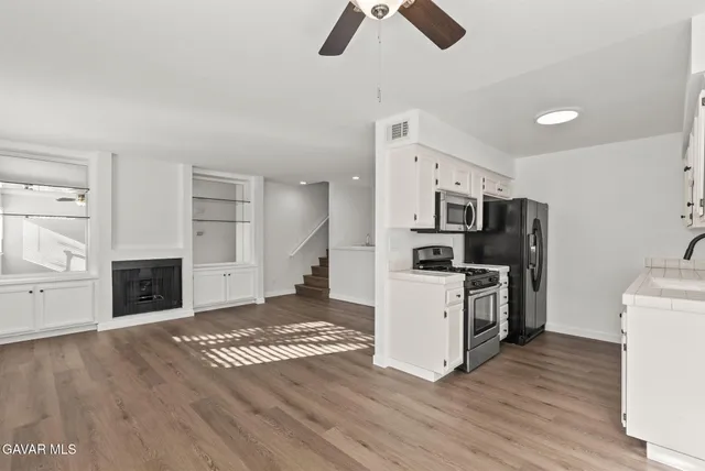 a kitchen with stainless steel appliances kitchen island hardwood floor sink and stove
