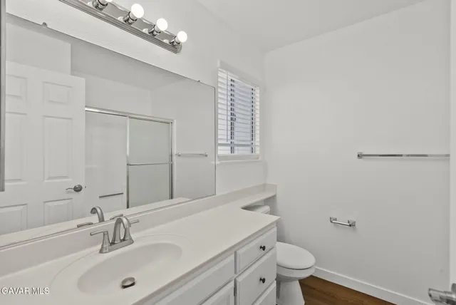 an empty room with wooden floor chandelier fan and windows