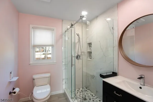a bathroom with a toilet a sink a mirror a vanity and shower