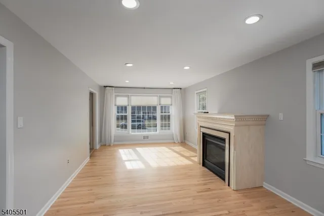 a view of empty room with wooden floor and fireplace