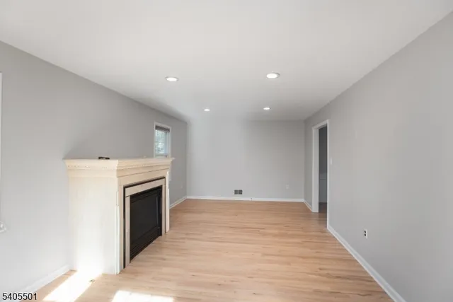 a view of empty room with wooden floor and fireplace