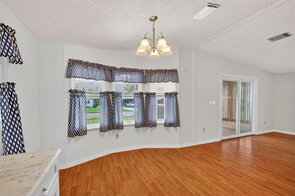 3324 Myakka River Road Tavares, FL 32778 - Photo 9 of 35 an empty room with wooden floor windows and chandelier