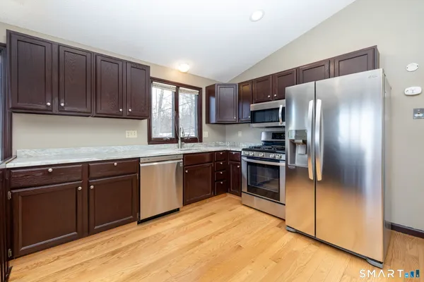 a kitchen with granite countertop wooden cabinets stainless steel appliances and a window