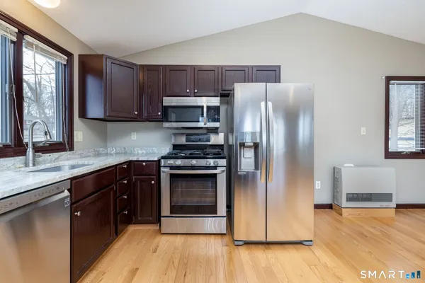 a kitchen with stainless steel appliances granite countertop a refrigerator a sink a stove a microwave and wooden cabinets