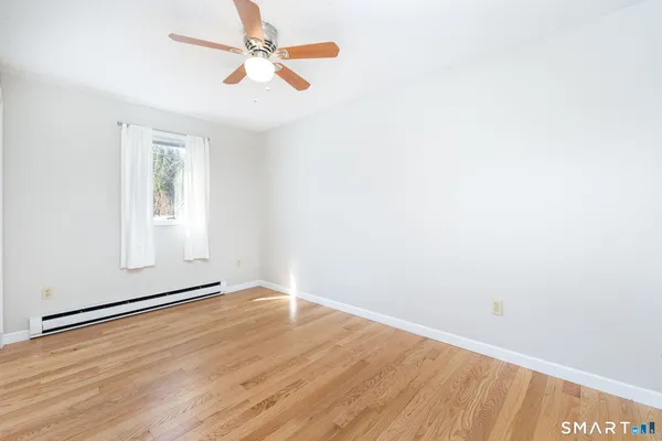 an empty room with wooden floor chandelier fan and windows