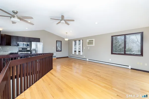 a view of a kitchen with furniture a ceiling fan and wooden floor