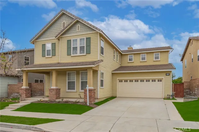 a view of brick house with a yard and large tree