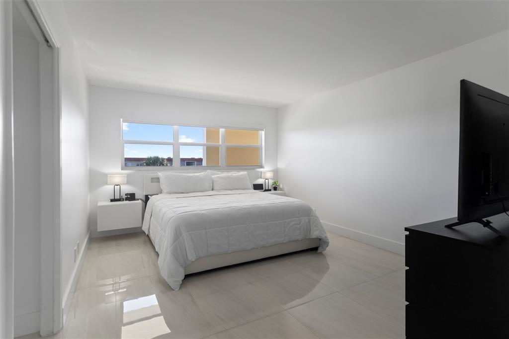 3100 Northeast 48th Court, Unit 413 Lighthouse Point, FL 33064 - Photo 11 of 32 a bedroom with a bed and a flat screen tv