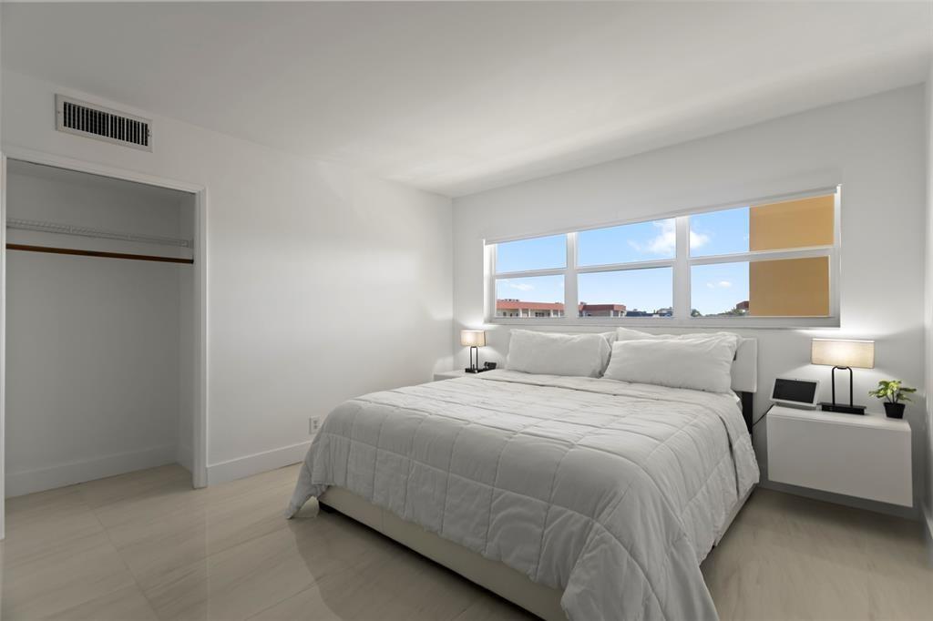 3100 Northeast 48th Court, Unit 413 Lighthouse Point, FL 33064 - Photo 12 of 32 a bedroom with a bed and a night stand