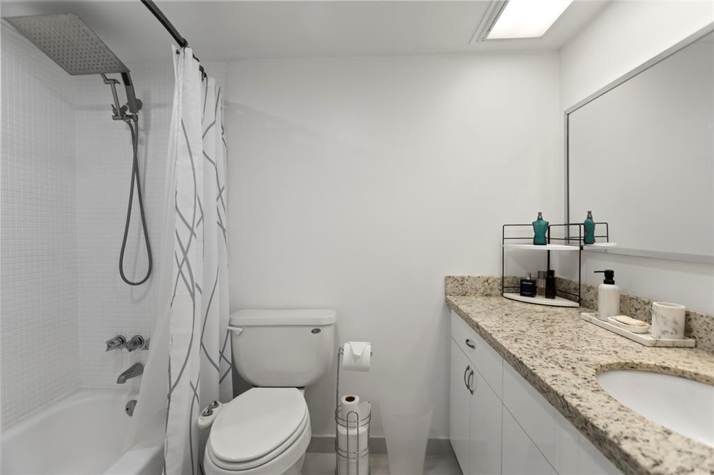 3100 Northeast 48th Court, Unit 413 Lighthouse Point, FL 33064 - Photo 15 of 32 a bathroom with a granite countertop sink toilet and shower