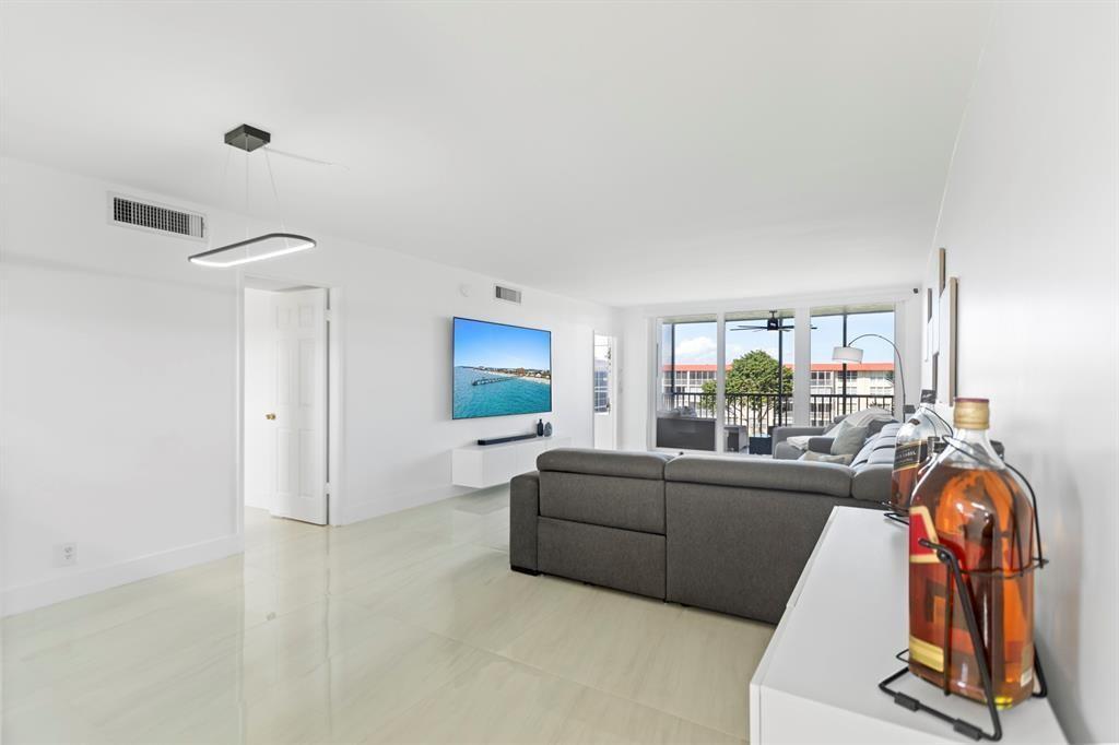 3100 Northeast 48th Court, Unit 413 Lighthouse Point, FL 33064 - Photo 3 of 32 a living room with furniture a floor to ceiling window and a flat screen tv