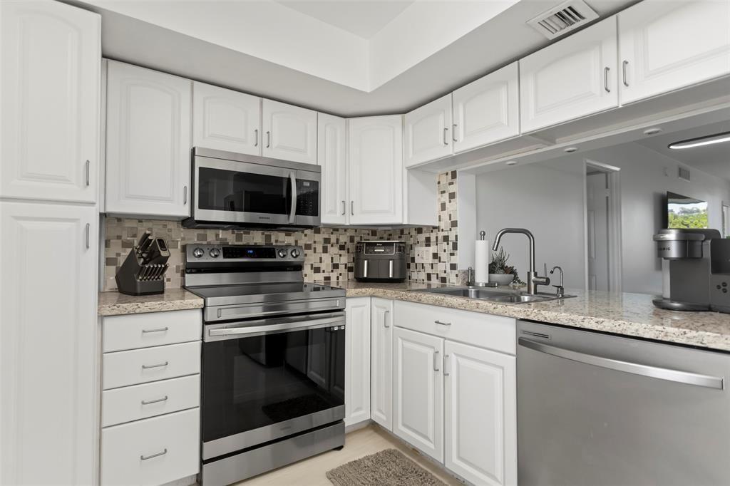 3100 Northeast 48th Court, Unit 413 Lighthouse Point, FL 33064 - Photo 8 of 32 a kitchen with granite countertop white cabinets white stainless steel appliances and a sink