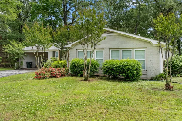 a view of a house with a big yard plants and large trees