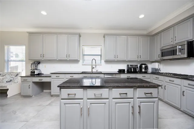 a kitchen with granite countertop white cabinets sink and stainless steel appliances
