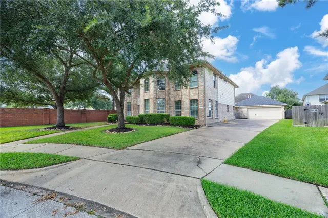 a view of a white house next to a yard with big trees