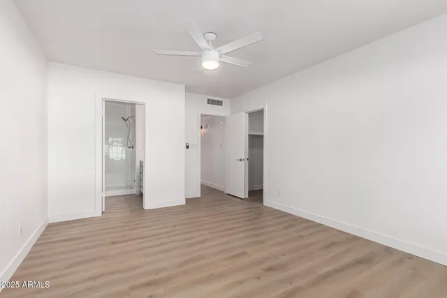 an empty room with wooden floor and a ceiling fan