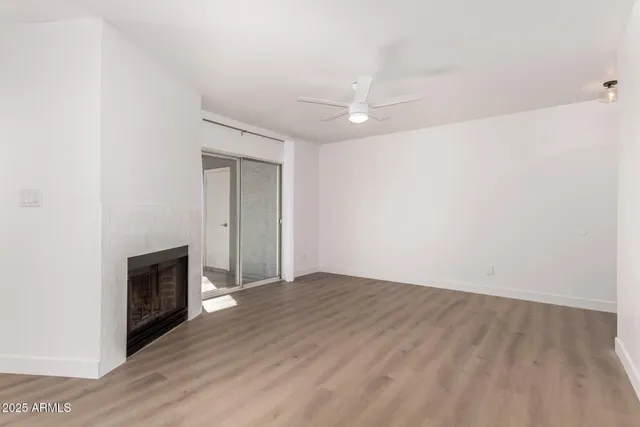 a view of an empty room with wooden floor and a fireplace