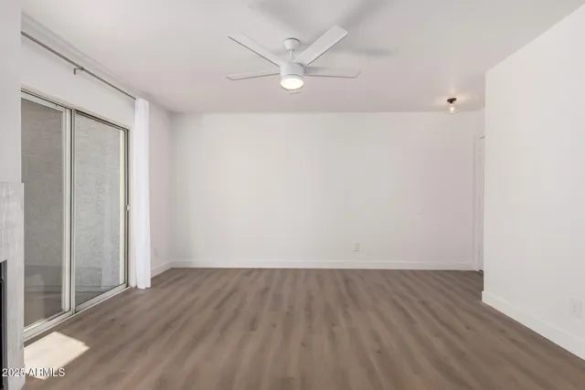 an empty room with wooden floor and a ceiling fan