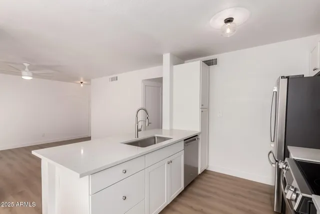 a kitchen with a sink refrigerator and wooden floor