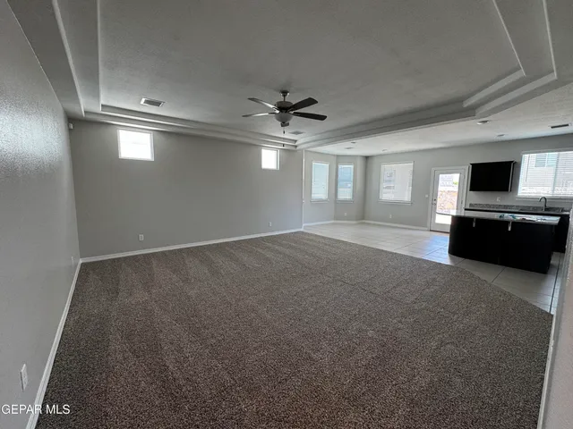 an empty room with windows and ceiling fan