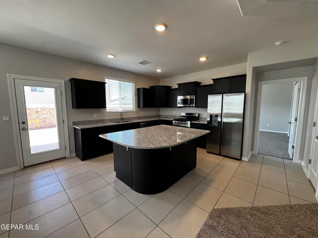 a large kitchen with stainless steel appliances granite countertop a refrigerator a sink a microwave and island