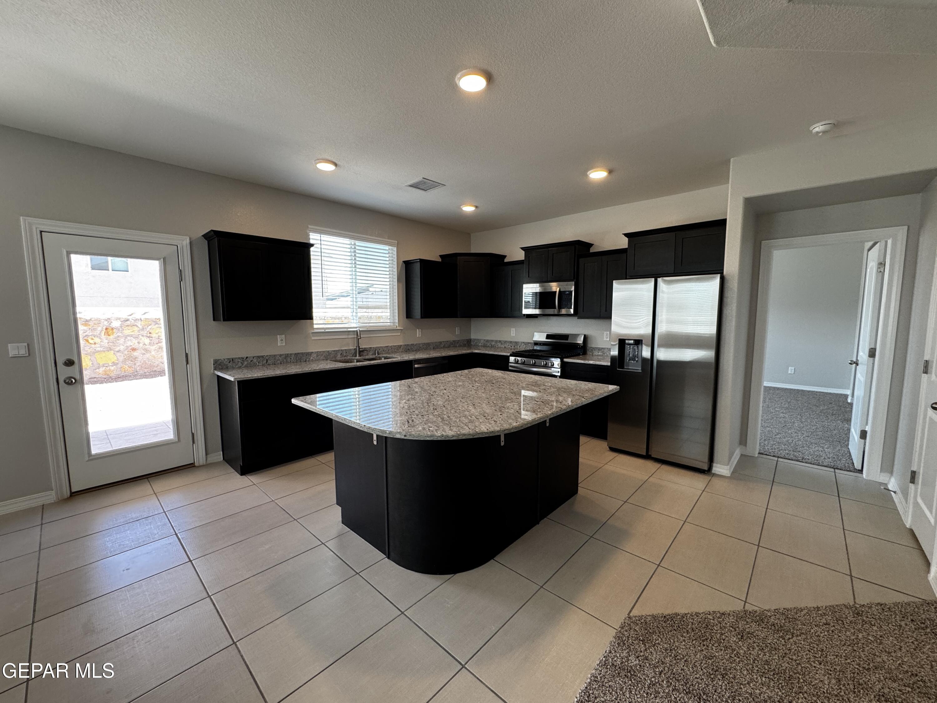 14434 Aria Lopez Drive El Paso, TX 79938 - Photo 3 of 37 a large kitchen with stainless steel appliances granite countertop a refrigerator a sink a microwave and island