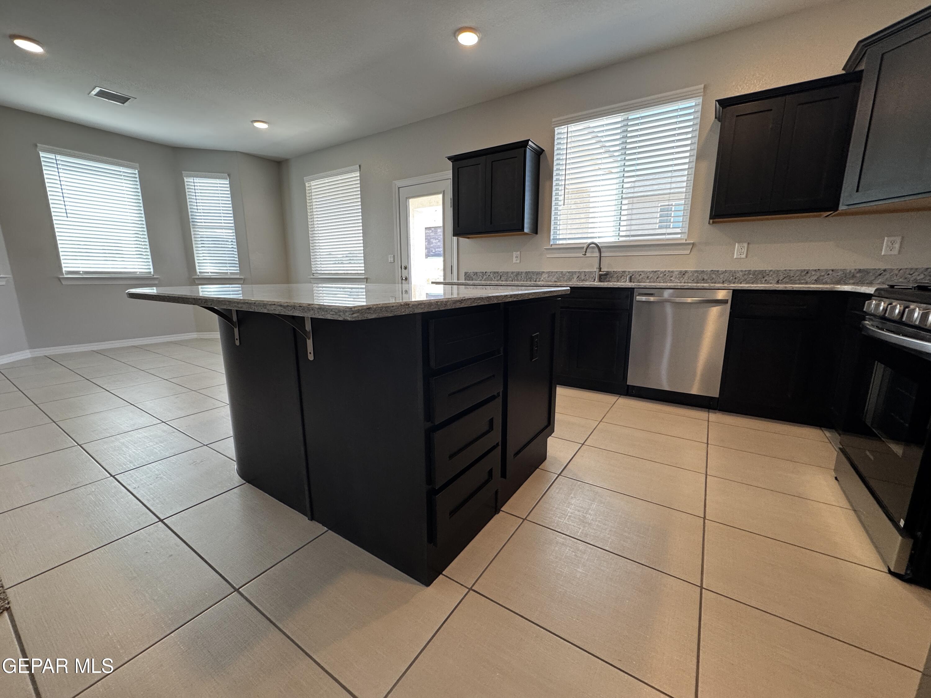14434 Aria Lopez Drive El Paso, TX 79938 - Photo 7 of 37 a kitchen with stainless steel appliances granite countertop a stove a sink and a microwave
