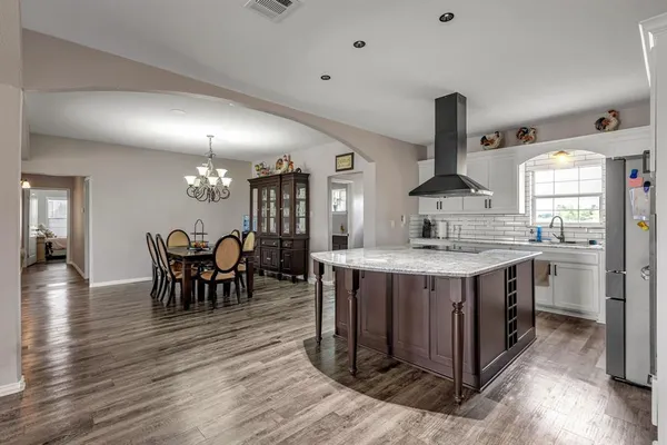a kitchen with stainless steel appliances granite countertop wooden floors and a view of living room