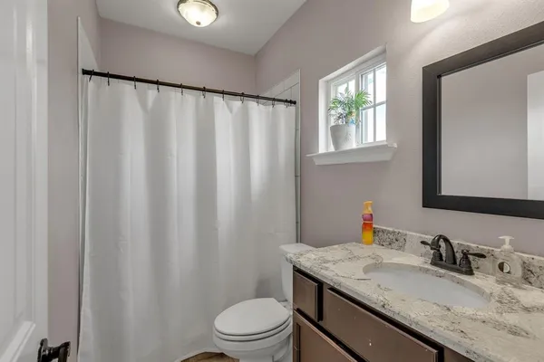 a bathroom with a granite countertop sink a toilet and a mirror