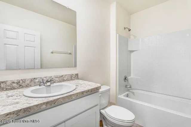 a bathroom with a granite countertop sink toilet a mirror and shower