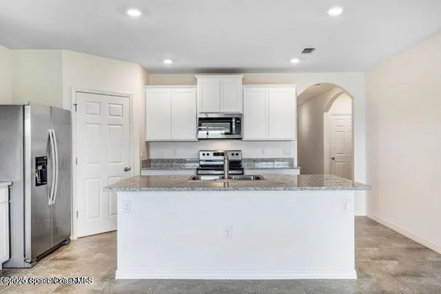a kitchen with stainless steel appliances granite countertop a sink a stove a refrigerator a microwave and cabinets
