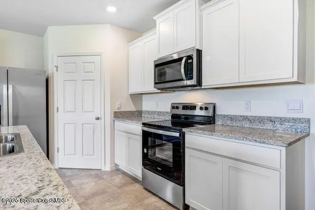 a kitchen with stainless steel appliances granite countertop white cabinets and a stove