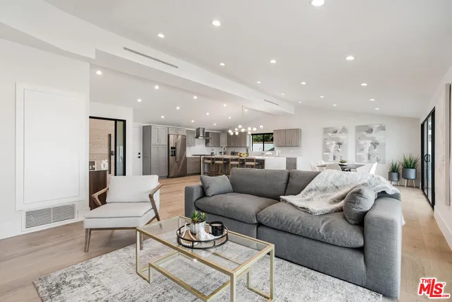 a living room with furniture kitchen view and a wooden floor
