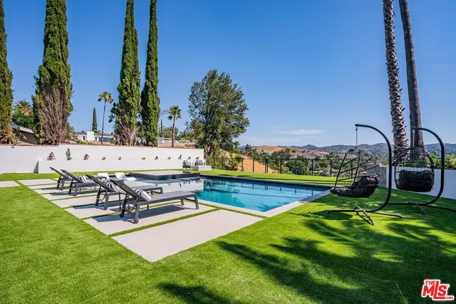 a view of a swimming pool with a yard and palm trees