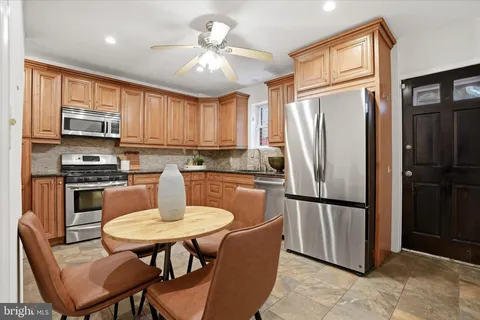 a kitchen with stainless steel appliances a refrigerator a stove a dining table and chairs