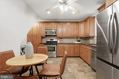 a kitchen with stainless steel appliances granite countertop a stove a sink dishwasher a dining table and chairs with wooden floor