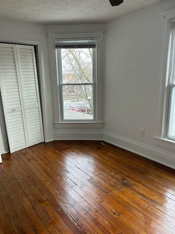 an empty room with wooden floor and windows