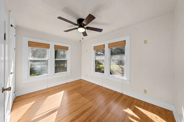 a view of an empty room with a window and wooden floor