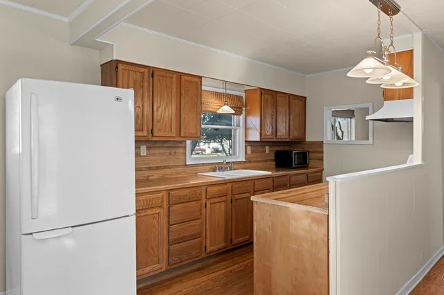 a kitchen with a refrigerator a stove a sink a center island and a window