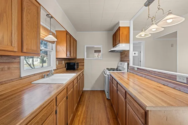 a kitchen with stainless steel appliances granite countertop a sink a stove and a wooden floors