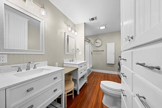 a bathroom with a sink a toilet a mirror and shower