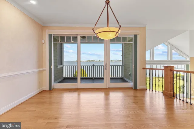 a view of an empty room with wooden floor and stairs