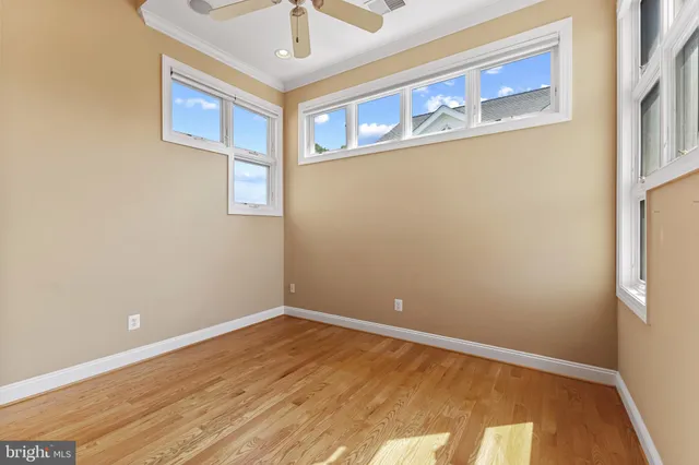 an empty room with chandelier fan and windows