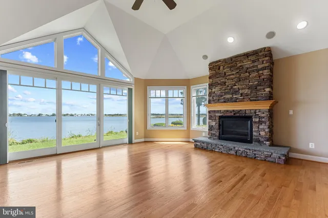 a view of an empty room with wooden floor fireplace and a window