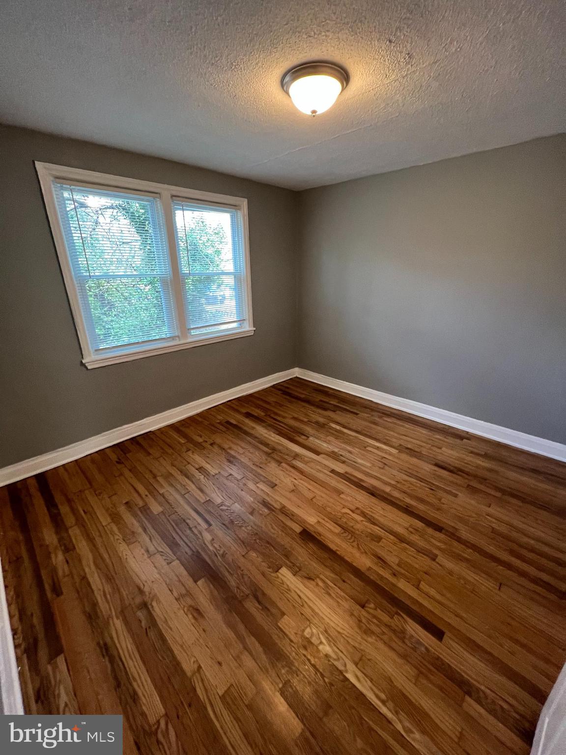 1102 Gleneagle Road Baltimore, MD 21239 - Photo 11 of 19 an empty room with wooden floor and windows