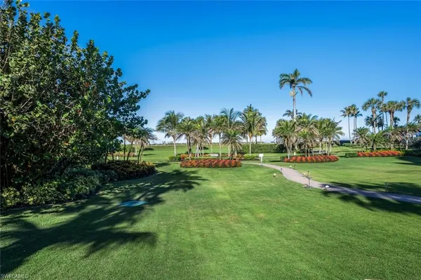 a view of a pathway both side of grassy field with shrub