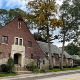 a front view of a house with a garden and tree